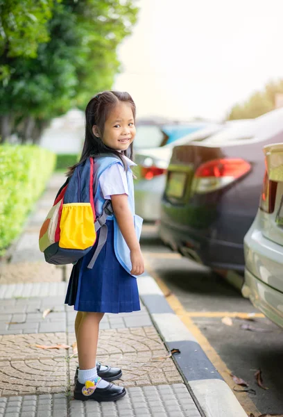 Tay okul üniforması içinde ayakta mutlu küçük kız portresi