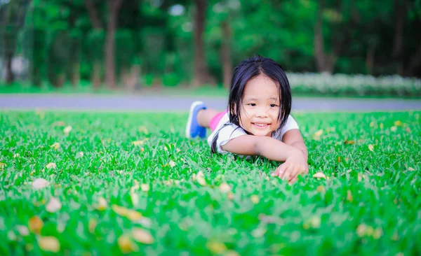 Ritratto di un carino asiatico bambina sdraiata su il terra e loo — Foto Stock