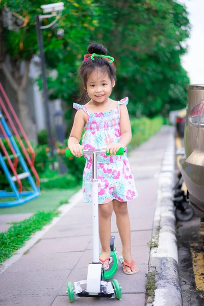 Cute Little Asian Girl uczenia się jeździć na skuterze na chodnik — Zdjęcie stockowe