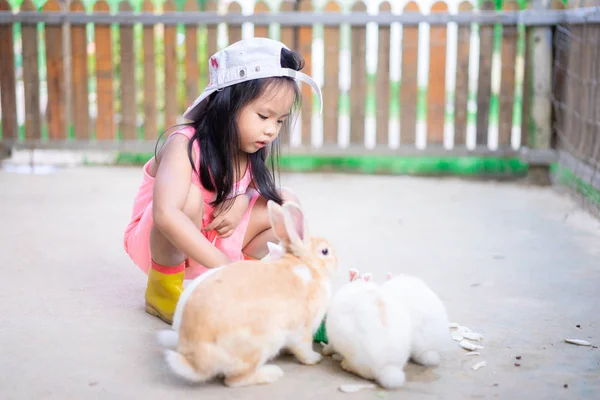 Cute Little Girl nosić kapelusz karmienia królika na farmie — Zdjęcie stockowe