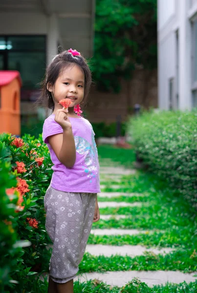 Portrait d'une mignonne petite fille avec une fleur rouge au pair — Photo