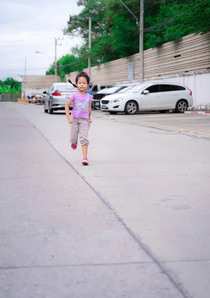 Egzersiz için sokaklarda koşan mutlu küçük kız.