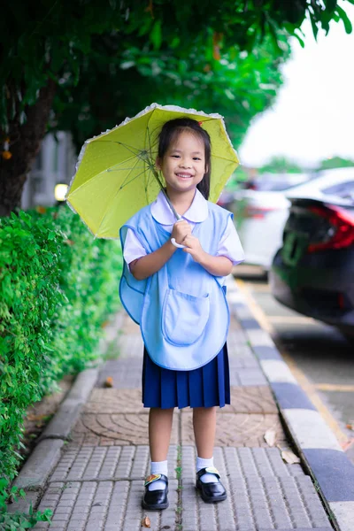 タイの女の子学校制服とともに黄色の傘でライニ — ストック写真