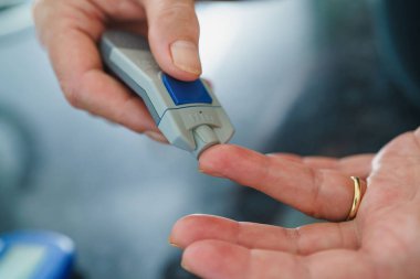 Tıp, Diyabet, Glisemi, Sağlık ve İnsan Konsepti - parmaklarda karyola kullanarak kan şekeri seviyesini Glikoz ölçer ile ölçmeye çalışan kadınlara yakın çekim