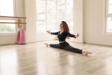 Stüdyoda spor yapan güzel, zayıf kız, derste esneme hareketleri yapıyor.