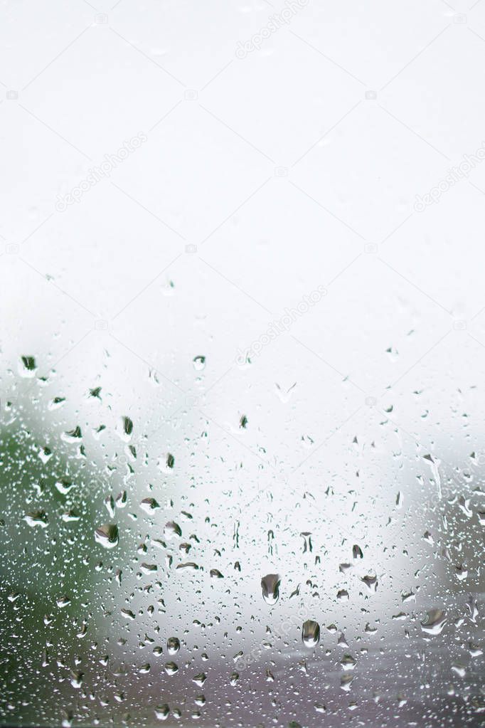 Rainy, autumn weather outside the window. Drops of water on the glass on a blurred background. Romantic grubby topic. Stock photo for design