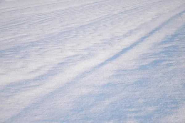 Sneeuwwitte sneeuw en de aarde erdoor beschut. Platteland en sneeuwval. Winterduinen en bergen sneeuwvlokken. Voorraad achtergrond. — Stockfoto