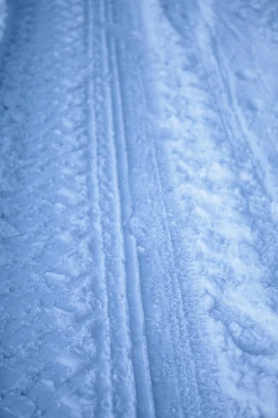 Struktura běhounu kol na sněhu. Zimní cesta v lednu, prosinci. Venkovská oblast a zázemí kolejí po traktoru ve sněhu — Stock fotografie