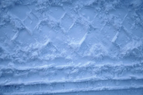 Loopvlaktextuur van autowielen op sneeuw. Winterweg in januari, december. Landelijk gebied en achtergrond van trekkersporen in de sneeuw — Stockfoto