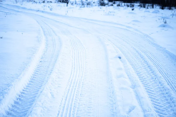 Laufflächenstruktur von Autorädern auf Schnee. Winterstraße im Januar, Dezember. ländlicher Raum und Hintergrund von Traktorspuren im Schnee — Stockfoto