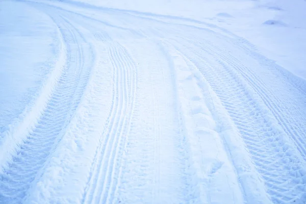 Loopvlaktextuur van autowielen op sneeuw. Winterweg in januari, december. Landelijk gebied en achtergrond van trekkersporen in de sneeuw — Stockfoto