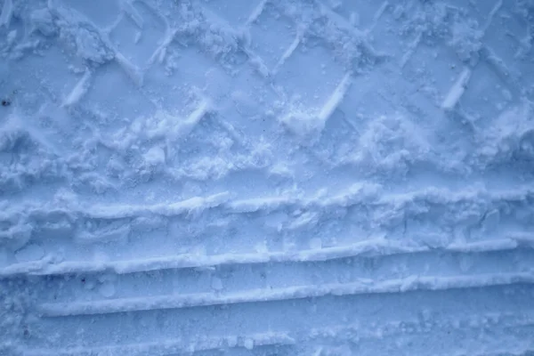Loopvlaktextuur van autowielen op sneeuw. Winterweg in januari, december. Landelijk gebied en achtergrond van trekkersporen in de sneeuw — Stockfoto