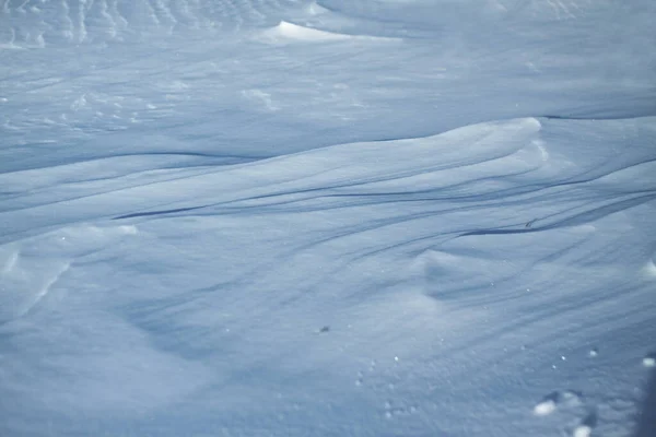 Sneeuwwitte sneeuw en de aarde erdoor beschut. Platteland en sneeuwval. Winterduinen en bergen sneeuwvlokken. Voorraad achtergrond. — Stockfoto