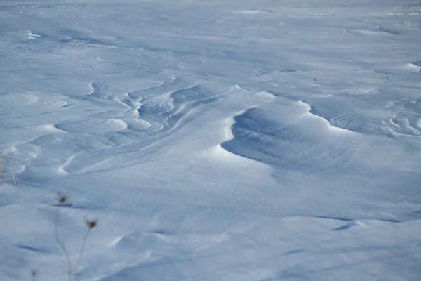 Sneeuwwitte sneeuw en de aarde erdoor beschut. Platteland en sneeuwval. Winterduinen en bergen sneeuwvlokken. Voorraad achtergrond. — Stockfoto