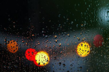 Yağmurlu bir caddeye bakan pencere. Yol manzaralı kasvetli bir akşam havası. Arabalardan camlara ve bokeh 'lere düşer. Tasarım için stok arkaplanı