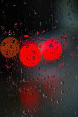 Yağmurlu bir caddeye bakan pencere. Yol manzaralı kasvetli bir akşam havası. Arabalardan camlara ve bokeh 'lere düşer. Tasarım için stok arkaplanı