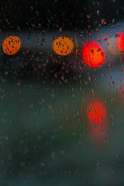 Yağmurlu bir caddeye bakan pencere. Yol manzaralı kasvetli bir akşam havası. Arabalardan camlara ve bokeh 'lere düşer. Tasarım için stok arkaplanı