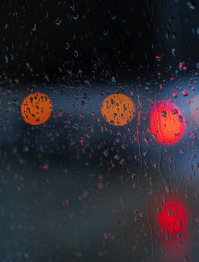 Yağmurlu bir caddeye bakan pencere. Yol manzaralı kasvetli bir akşam havası. Arabalardan camlara ve bokeh 'lere düşer. Tasarım için stok arkaplanı