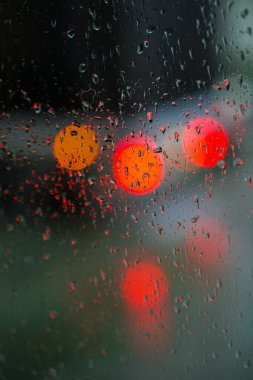Yağmurlu bir caddeye bakan pencere. Yol manzaralı kasvetli bir akşam havası. Arabalardan camlara ve bokeh 'lere düşer. Tasarım için stok arkaplanı