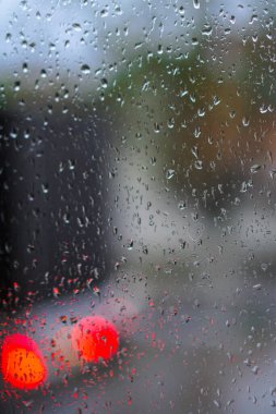Yağmurlu bir caddeye bakan pencere. Yol manzaralı kasvetli bir akşam havası. Arabalardan camlara ve bokeh 'lere düşer. Tasarım için stok arkaplanı