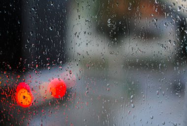 Yağmurlu bir caddeye bakan pencere. Yol manzaralı kasvetli bir akşam havası. Arabalardan camlara ve bokeh 'lere düşer. Tasarım için stok arkaplanı