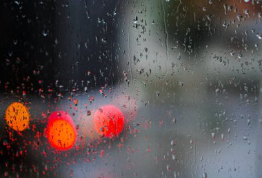 Yağmurlu bir caddeye bakan pencere. Yol manzaralı kasvetli bir akşam havası. Arabalardan camlara ve bokeh 'lere düşer. Tasarım için stok arkaplanı