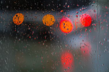 Yağmurlu bir caddeye bakan pencere. Yol manzaralı kasvetli bir akşam havası. Arabalardan camlara ve bokeh 'lere düşer. Tasarım için stok arkaplanı