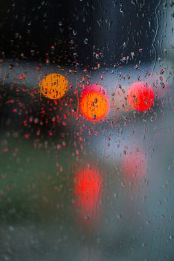Yağmurlu bir caddeye bakan pencere. Yol manzaralı kasvetli bir akşam havası. Arabalardan camlara ve bokeh 'lere düşer. Tasarım için stok arkaplanı