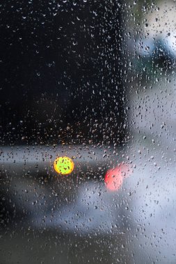Yağmurlu bir caddeye bakan pencere. Yol manzaralı kasvetli bir akşam havası. Arabalardan camlara ve bokeh 'lere düşer. Tasarım için stok arkaplanı
