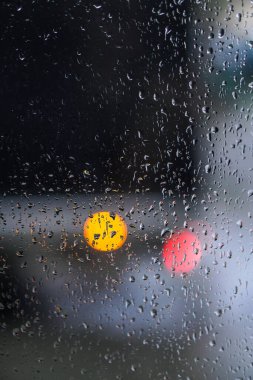Yağmurlu bir caddeye bakan pencere. Yol manzaralı kasvetli bir akşam havası. Arabalardan camlara ve bokeh 'lere düşer. Tasarım için stok arkaplanı