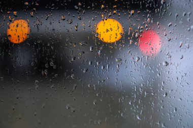 Yağmurlu bir caddeye bakan pencere. Yol manzaralı kasvetli bir akşam havası. Arabalardan camlara ve bokeh 'lere düşer. Tasarım için stok arkaplanı