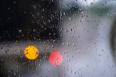 Yağmurlu bir caddeye bakan pencere. Yol manzaralı kasvetli bir akşam havası. Arabalardan camlara ve bokeh 'lere düşer. Tasarım için stok arkaplanı