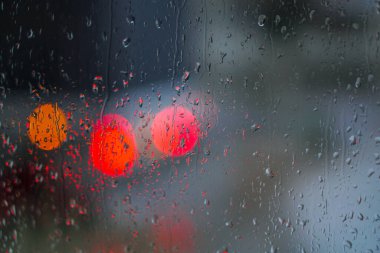 Yağmurlu bir caddeye bakan pencere. Yol manzaralı kasvetli bir akşam havası. Arabalardan camlara ve bokeh 'lere düşer. Tasarım için stok arkaplanı