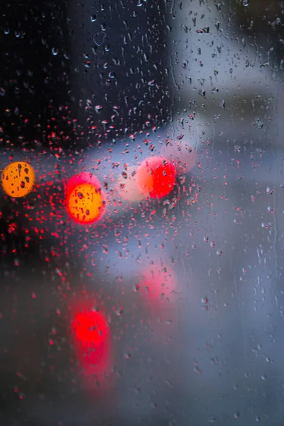 Yağmurlu bir caddeye bakan pencere. Yol manzaralı kasvetli bir akşam havası. Arabalardan camlara ve bokeh 'lere düşer. Tasarım için stok arkaplanı