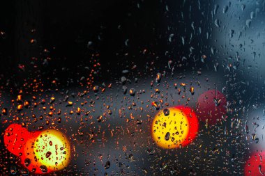 Yağmurlu bir caddeye bakan pencere. Yol manzaralı kasvetli bir akşam havası. Arabalardan camlara ve bokeh 'lere düşer. Tasarım için stok arkaplanı