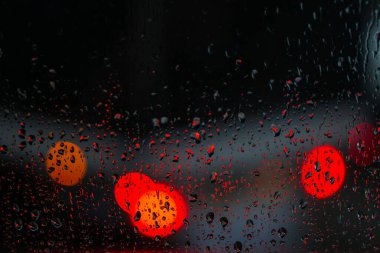 Yağmurlu bir caddeye bakan pencere. Yol manzaralı kasvetli bir akşam havası. Arabalardan camlara ve bokeh 'lere düşer. Tasarım için stok arkaplanı
