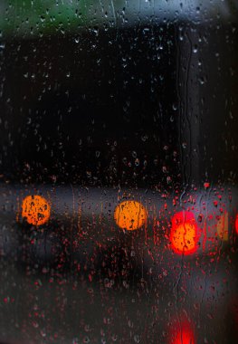 Yağmurlu bir caddeye bakan pencere. Yol manzaralı kasvetli bir akşam havası. Arabalardan camlara ve bokeh 'lere düşer. Tasarım için stok arkaplanı
