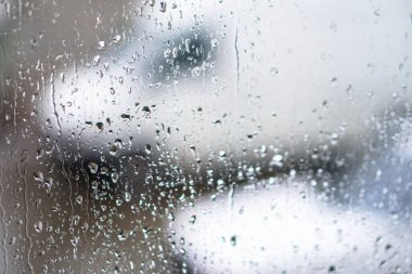 Yağmurlu bir caddeye bakan pencere. Yol manzaralı kasvetli bir akşam havası. Arabalardan camlara ve bokeh 'lere düşer. Tasarım için stok arkaplanı