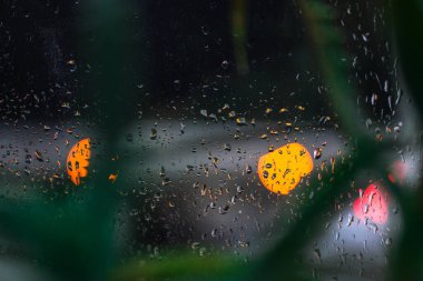 Yağmurlu bir caddeye bakan pencere. Yol manzaralı kasvetli bir akşam havası. Arabalardan camlara ve bokeh 'lere düşer. Tasarım için stok arkaplanı