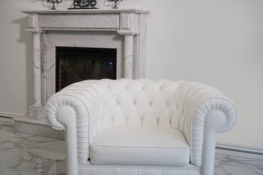 Beyaz deri koltuk, şöminenin arka planında..