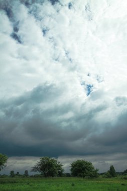 Eski bahçenin yakınındaki bir tarlada gök gürültülü destansı bulutlar. Cennetteki stok fotoğrafı arkaplanı.