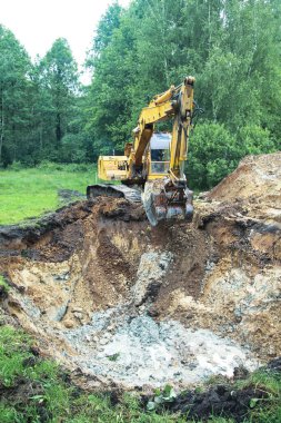 Bir kazıcı ev inşa etmek için büyük bir çukur kazar. Bir traktör zaten su kazanan büyük bir göl kazıyor. Tasarım için stok arkaplanı