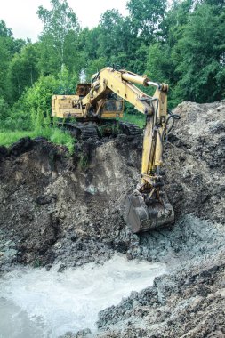 Bir kazıcı ev inşa etmek için büyük bir çukur kazar. Bir traktör zaten su kazanan büyük bir göl kazıyor. Tasarım için stok arkaplanı