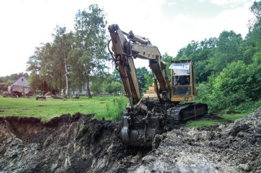 Bir kazıcı ev inşa etmek için büyük bir çukur kazar. Bir traktör zaten su kazanan büyük bir göl kazıyor. Tasarım için stok arkaplanı