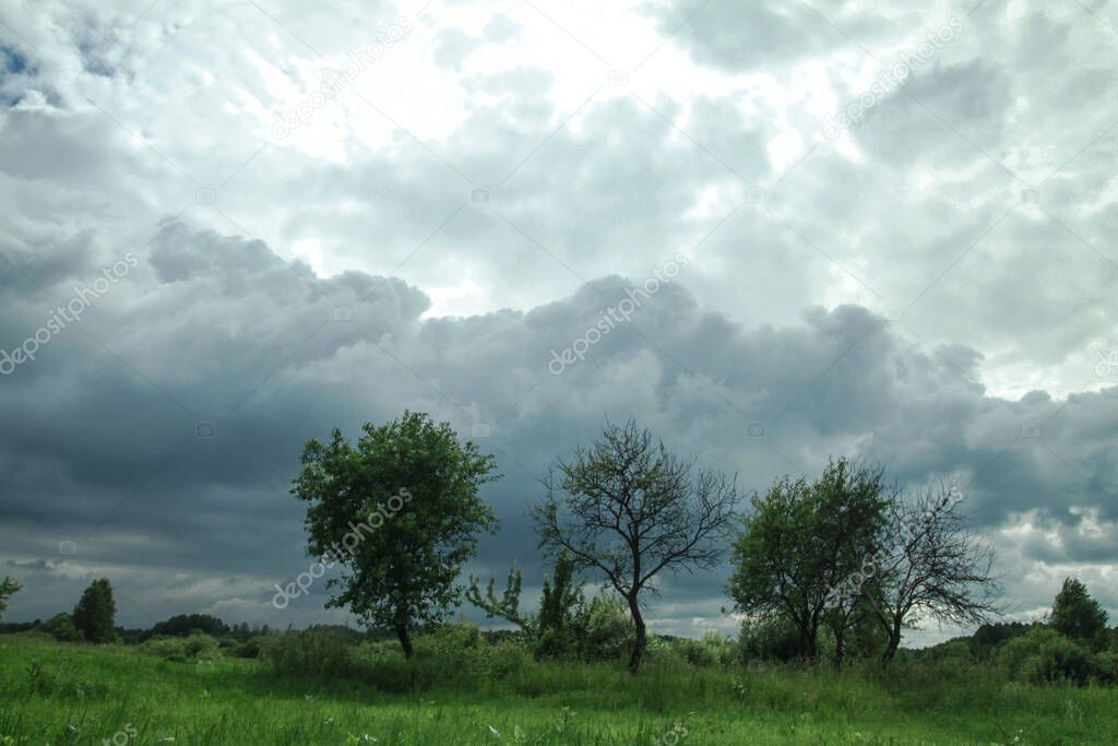 Thunderous epic clouds in a field near the old garden. Stock photo background with heaven.