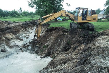 Bir kazıcı ev inşa etmek için büyük bir çukur kazar. Bir traktör zaten su kazanan büyük bir göl kazıyor. Tasarım için stok arkaplanı
