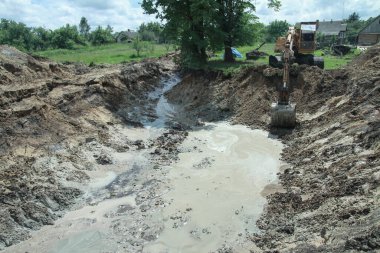 Bir kazıcı ev inşa etmek için büyük bir çukur kazar. Bir traktör zaten su kazanan büyük bir göl kazıyor. Tasarım için stok arkaplanı