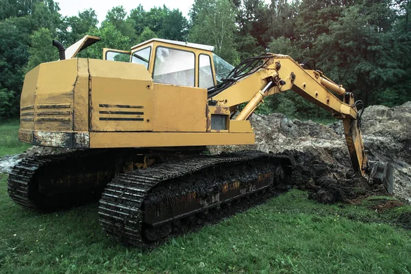 An excavator digs a large trench for building a house. A tractor digs a large lake that is already gaining water. Stock background for design