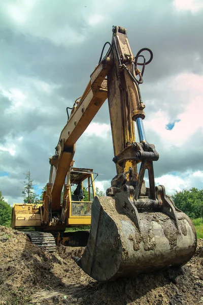 An excavator digs a large trench for building a house. A tractor digs a large lake that is already gaining water. Stock background for design