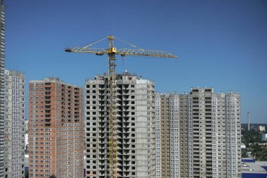 İnşaat sırasında çok aşamalı inşaat ve sarı bir vinç. Tasarım için endüstriyel arkaplan.